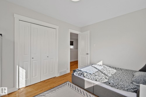 Light gray walls, light wood-finish flooring, white bi-fold closet doors, white trim, and a flush-mount ceiling light - 12403 29A Avenue Nw, Edmonton, AB 