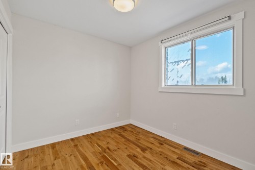 Warm wood-finish flooring, a large window with white trim, and a flush mount ceiling light fixture - 12403 29A Avenue Nw, Edmonton, AB 