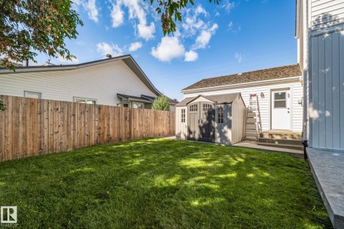 Expansive green lawn, wood fence, white vinyl siding, exterior storage shed, and exterior entry - 12403 29A Avenue Nw, Edmonton, AB 