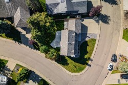 Stone veneer exterior, gabled roofline, concrete driveway, mature trees, manicured lawn - 