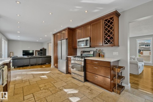 Kitchen featuring wood cabinetry, stainless steel appliances, stone tile flooring, and light-toned countertops - 12403 29A Avenue Nw, Edmonton, AB 