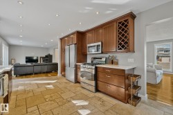 Kitchen featuring wood cabinetry, stainless steel appliances, stone tile flooring, and light-toned countertops - 