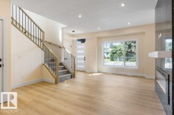 Bright and spacious open-concept living area featuring gleaming wood-finish flooring, recessed ceiling lighting, and abundant natural light from expansive windows - 