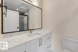 3 Piece Ensuite Bathroom featuring a white vanity with gold-veined countertop, integrated sink, and modern brass-finish faucet - 