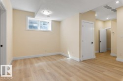 Spacious room featuring wood-finish flooring, light-toned walls, and white baseboards - 