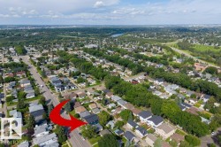 Aerial perspective of a residential street with mature trees and a distant river - 
