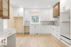 Bright kitchen featuring white cabinetry with gold-tone hardware, a light wood-finish floor, and a white countertop with a matching backsplash - 