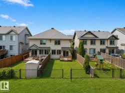 Expansive fenced backyard featuring a manicured lawn, wood deck, and a storage shed - 