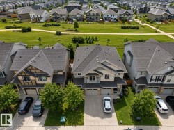Suburban residence featuring a two-car garage, mature front yard trees, and a paved driveway - 