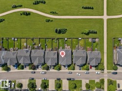 Property featuring a gray shingle roof, paved driveway, and established landscaping - 