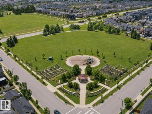 Expansive green space featuring a playground, multiple garden plots, a paved walking path, and a central gazebo - 1668 Chapman Way Sw, Edmonton, AB 