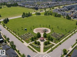 Expansive green space featuring a playground, multiple garden plots, a paved walking path, and a central gazebo - 
