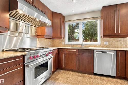 Gourmet kitchen featuring a stainless steel range and hood, wood cabinetry, stone countertops, and tile flooring - 14103 60 Avenue Nw, Edmonton, AB 