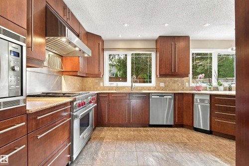 Wood cabinetry with stainless steel appliances, stone countertops, and tile flooring - 14103 60 Avenue Nw, Edmonton, AB 