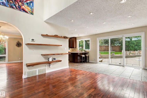 Hardwood flooring throughout, vaulted ceiling, built-in wooden shelving, recessed lighting, and sliding glass patio doors - 14103 60 Avenue Nw, Edmonton, AB 