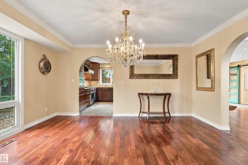 Hardwood flooring, crystal chandelier, arched doorways, crown molding, and a kitchen with dark wood cabinetry and stainless steel appliances - 14103 60 Avenue Nw, Edmonton, AB 