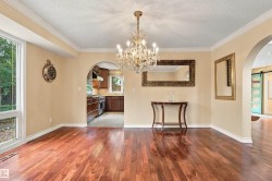 Hardwood flooring, crystal chandelier, arched doorways, crown molding, and a kitchen with dark wood cabinetry and stainless steel appliances - 