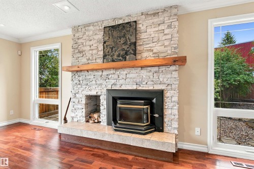 Stone-faced fireplace with a wood-burning insert and a substantial wood mantel - 14103 60 Avenue Nw, Edmonton, AB 