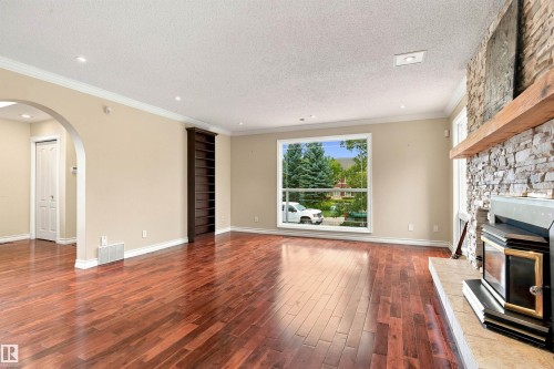 Hardwood flooring throughout, stone-clad fireplace with wood mantle, built-in shelving, arched doorway, and recessed lighting - 14103 60 Avenue Nw, Edmonton, AB 