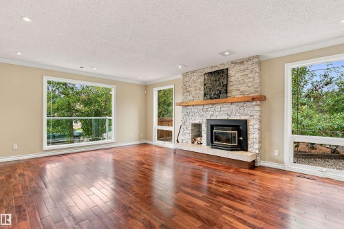 Hardwood flooring, stone-clad fireplace with wood mantel, large windows, recessed lighting, and crown molding - 14103 60 Avenue Nw, Edmonton, AB 