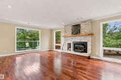 Hardwood flooring, stone-clad fireplace with wood mantel, large windows, recessed lighting, and crown molding - 
