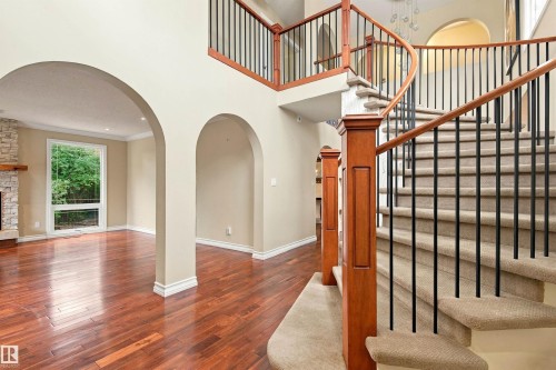 Grand entry featuring a curved staircase with carpeted treads and wrought iron spindles - 14103 60 Avenue Nw, Edmonton, AB 