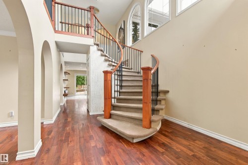Curved staircase with wood-finish handrails and wrought iron balusters - 14103 60 Avenue Nw, Edmonton, AB 