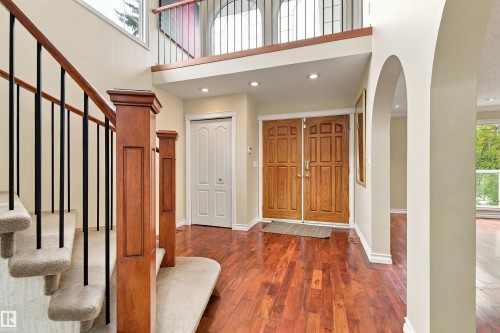 Double-door entry with wood-finish flooring, two-story foyer, curved archways, and a staircase with wrought iron balusters - 14103 60 Avenue Nw, Edmonton, AB 
