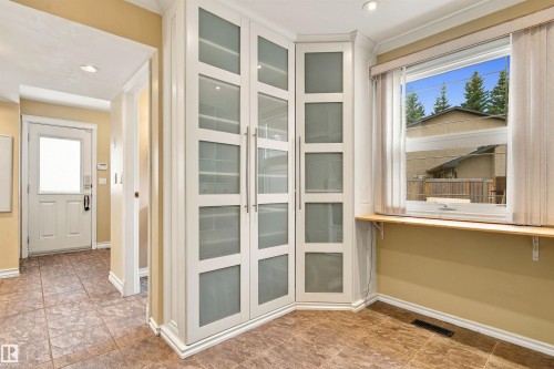 Built-in corner cabinetry with frosted glass panels, wood-finish flooring, white trim, and a window with a wood sill - 14103 60 Avenue Nw, Edmonton, AB 