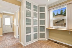 Built-in corner cabinetry with frosted glass panels, wood-finish flooring, white trim, and a window with a wood sill - 