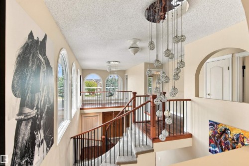 Multi-level interior featuring a decorative chandelier, arched windows, and dark wood-finish flooring - 14103 60 Avenue Nw, Edmonton, AB 