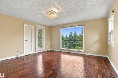Wood-finish flooring, neutral wall paint, white trim, multiple windows, and a glass-paneled door - 14103 60 Avenue Nw, Edmonton, AB 