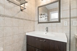 Bathroom featuring a wood-finish vanity with an integrated sink, polished chrome faucet, and a decorative framed mirror - 
