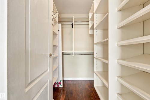 Walk-in closet featuring wood-finish flooring, built-in shelving, and hanging rods - 14103 60 Avenue Nw, Edmonton, AB 