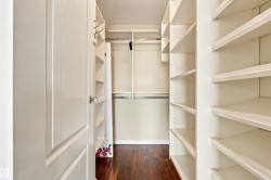 Walk-in closet featuring wood-finish flooring, built-in shelving, and hanging rods - 