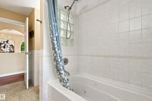 Jetted bathtub with white subway tile surround, chrome fixtures, and a glass block window - 14103 60 Avenue Nw, Edmonton, AB 