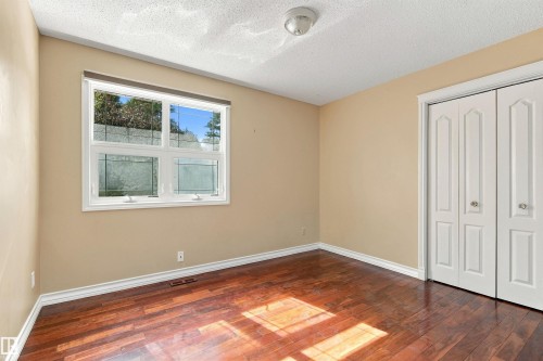 Wood-finish flooring, neutral wall tones, a double-panel window, and bi-fold closet doors - 14103 60 Avenue Nw, Edmonton, AB 