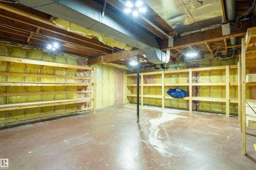 Unfinished lower level featuring concrete flooring, exposed ceiling joists, built-in wooden shelving, insulation, and recessed lighting fixtures - 14103 60 Avenue Nw, Edmonton, AB 