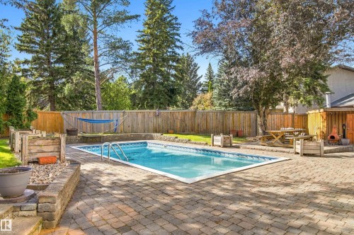 Expansive backyard featuring a rectangular in-ground pool, paver patio, wood privacy fencing, and mature trees - 14103 60 Avenue Nw, Edmonton, AB 