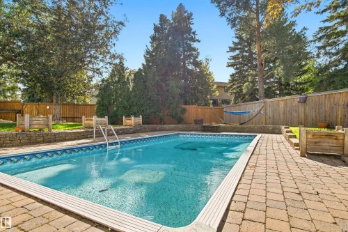 Outdoor swimming pool with integrated steps, surrounded by a paver patio and a wood privacy fence - 14103 60 Avenue Nw, Edmonton, AB 