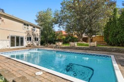 Outdoor swimming pool with brick paver surround, stucco exterior, stone accent cladding, and large sliding glass doors - 