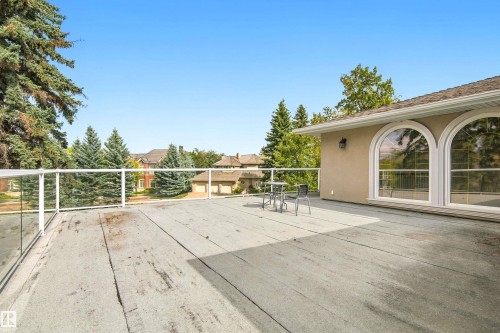 Expansive outdoor deck featuring glass panel railings, a stucco exterior, and two large arched windows - 14103 60 Avenue Nw, Edmonton, AB 