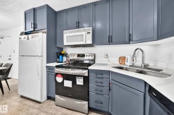 Kitchen featuring shaker-style cabinetry, stainless steel appliances, a corner sink, and light-toned countertops - 