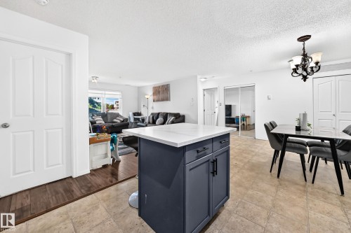 Kitchen island with white countertop and dark cabinetry - #133 16311 95 St Nw, Edmonton, AB 