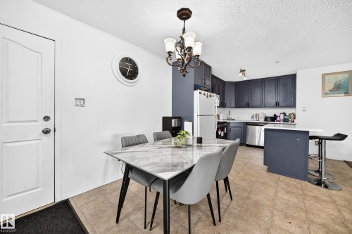 Kitchen featuring dark cabinetry, stainless steel appliances, and a breakfast bar - #133 16311 95 St Nw, Edmonton, AB 