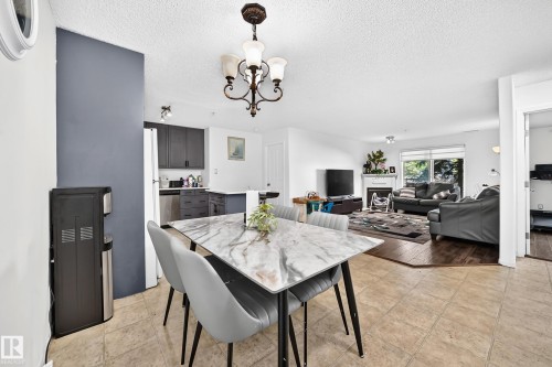 Open-concept dining area with tile flooring and a decorative chandelier - #133 16311 95 St Nw, Edmonton, AB 