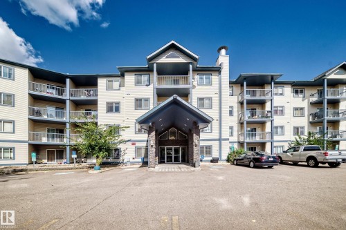 Multi-story building featuring multiple private balconies, a covered entrance, and an asphalt parking area - #133 16311 95 St Nw, Edmonton, AB 