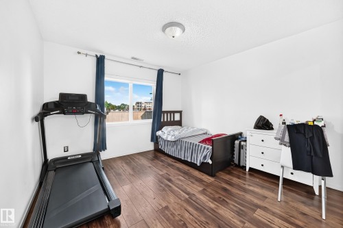 Wood-finish flooring and white walls with a window featuring blue drapes - #133 16311 95 St Nw, Edmonton, AB 