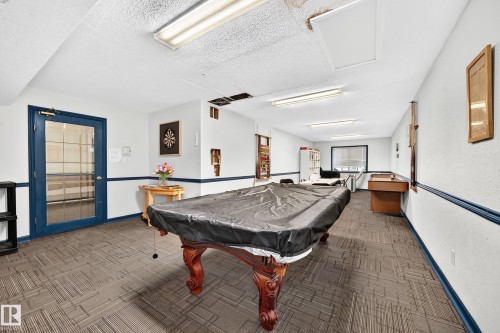 Spacious recreation area featuring patterned carpet flooring and a glass-paneled door - #133 16311 95 St Nw, Edmonton, AB 