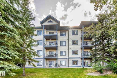 Multi-story building featuring private balconies, ground-level patios, a gabled roofline, and mature perimeter trees - #133 16311 95 St Nw, Edmonton, AB 